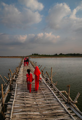 children with red clothes, crosses old traditional bamboo wooden bridge across Mekong river (from Koh Paen island to Kampong Cham), Cambodia