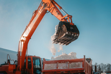 Snow removal after snowfall and blizzards. Excavator loads snow into a truck