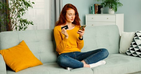 Pretty girl buying on smartphone and paying with credit card,  stay at home.