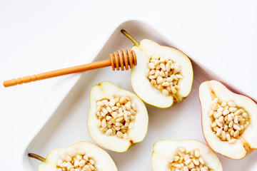 Sweet pears with honey, nuts and cinnamon before baking. Top view of dessert on white background