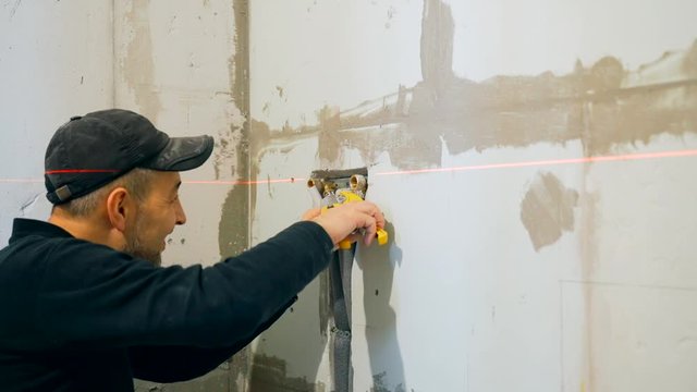 Male plumber works in bathroom, installs plastic pipes, hot and cold water.