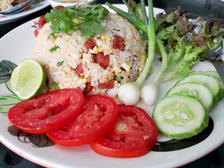 Chinese sausage fried rice with fresh tomatoes, spring onions, lime, cucumbers and lettuce as a side dish.
