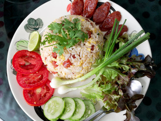 Chinese sausage fried rice with fresh tomatoes, spring onions, lime, cucumbers and lettuce as a side dish.