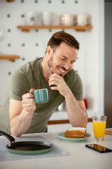 Obraz na płótnie Canvas Handsome man preparing breakfast at home. Young man drinking coffee in kitchen.