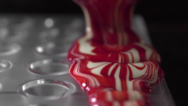 pouring liquid white colored chocolate to the candys molds