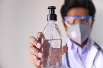 Doctor with face mask holding sanitizer with copy space 