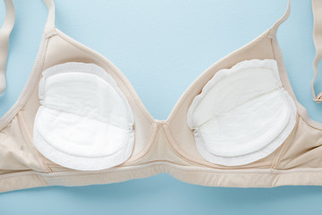 White breast pads in bra on light blue table background. Pastel color. Clothes protection in...