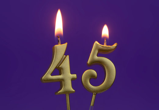 Burning golden birthday candles on blue background, number 45