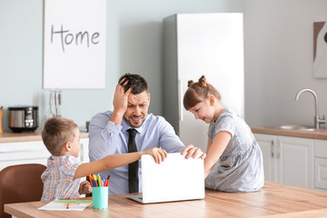 Little children keeping father from his work at home