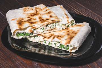 cannelloni, cottage cheese with greens in pita bread on a plate