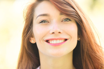 Caucasian woman smiling happy on sunny summer or spring day outside in park. Close up of red head model. Happy face.