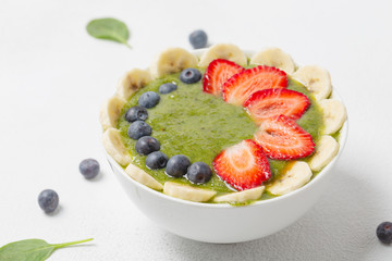 Green smoothie bowl with spinach,fresh kiwi fruit, bananas, blueberries and strawberries. Clean eating, weight loss food concept. Close up.