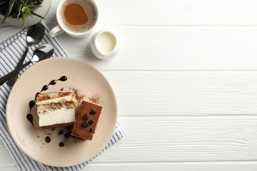 Composition with tasty tiramisu and cocoa drink on white wooden table. Delicious dessert