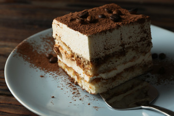 Plate with tiramisu and cake shovel on wooden background