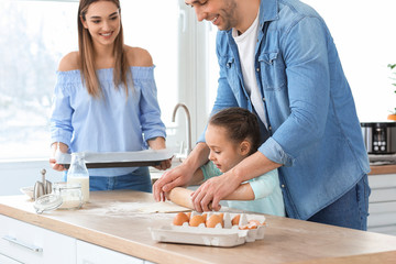 Obraz na płótnie Canvas Happy family making dough together in kitchen