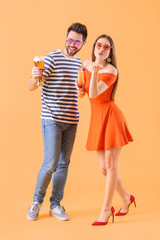 Happy young couple with alcoholic drinks on color background