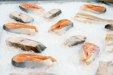 Slices of diverse fish lie on ice. Red and white sea fish