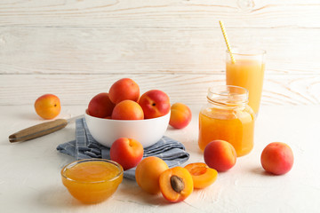 Composition with apricots, juice and jam on white table