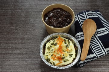Famous sweet dessert in bakery shop. Dark chocolate fudge cup cake in paper container and traditional carrot cheese cake in aluminium foil tray. Welcome snack in celebration party.