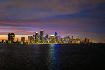 Fototapeta na wymiar Miami city skyline panorama with urban skyscrapers over sea with reflection. Miami downtown view at night. Downtown Miami city center.