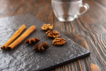 Anise star and cinnamon sticks on a stone tile, go for coffee, in the background an empty glass cup. Coffee seasoning concept.