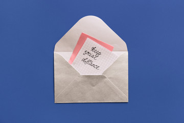 Envelope and paper with text KEEP SOCIAL DISTANCE on color background