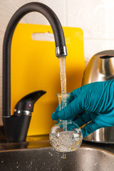 A specialist pours tap water into a glass flask.