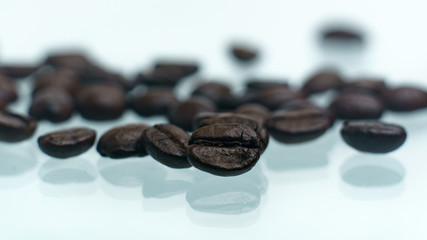 Roasted coffee beans pile on white glass reflection background
