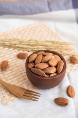 Almonds in wood bowl on wooden background. Almonds with wood spoon and fork and Ears of rice on fabric background