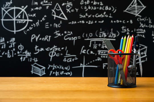 Education background concept. Stationery in holder color pencil, compasses tool, scissors, rulers, sharpener On chalkboard with the Mathematical formula background.