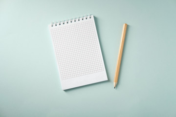 Notebook and pencil on a blue background, top view