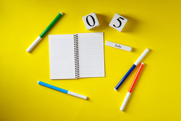 Date on the calendar July 5, notebook, felt-tip pens, on a yellow background