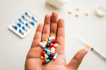 Close up hand holding medicine pills on white table background.
