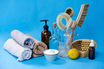 Obraz na płótnie Canvas natural cleaning stuff, sustainability and eco living concept - lemon halves, washing soda, bottle of vinegar with laundry and liquid soap and brushes on blue background