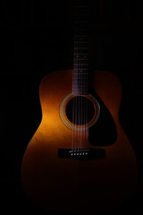 Acoustic guitar detail on a black background between light or shadows