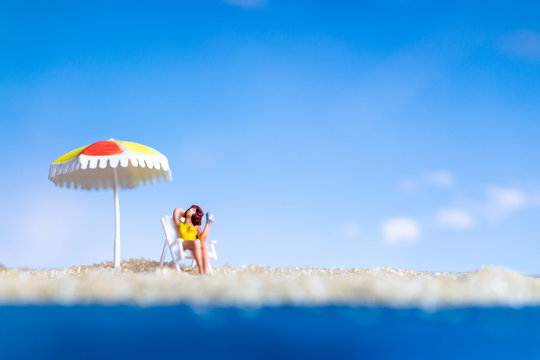 Miniature people sunbathing on The baech with blue sky background , Summer time concept