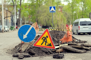 road sign, detour, road repair on the background of the road and broken asphalt covering on the...