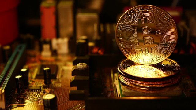 Golden coins with bitcoin symbol on a main board computer. 