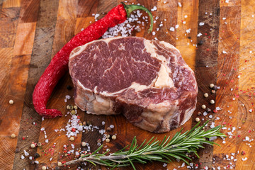 Raw fresh meat Ribeye Steak with pepper and salt on wooden background