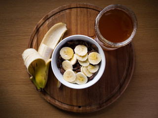 Healthy breakfast, cereals bowl with honey and banana on wooden background