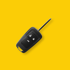 New black car key on yellow background with light shadow.