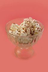 ice cream with whipped cream and chocolate chips on a pink backg
