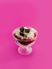 whipped cream dessert with grated chocolate and pieces of chocolate and jam in a glass bowl