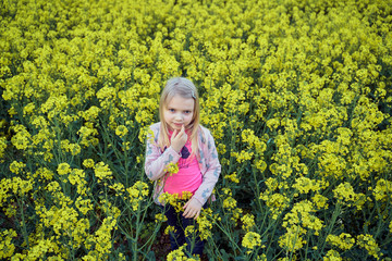 Fototapeta premium young girl in a rapeseed field in the spring evening