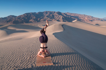 Young beautiful woman makes yoga fitness exercise on the sand mountain at sunset. Health lifestyle...