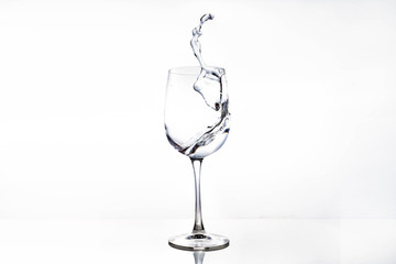 Water in a wine glass. Splash of liquid on a white background. Isolated object. Spray. Selective focus.