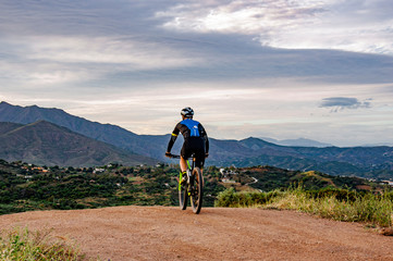 Cyclist rides a mountain bike on a mountain road in the background of mountains