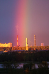 Obraz na płótnie Canvas Bright rainbow above the city over bridge and factory pipes