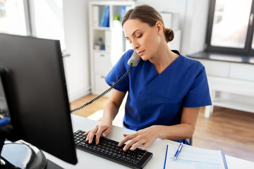 medicine, technology and healthcare concept - female doctor or nurse with computer calling on phone...