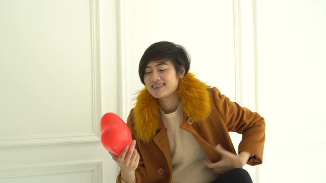 Asian short hair woman happy in love holding red heart balloon smiling and laughing